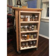 a wooden spice rack on wheels with jars and spices in the bottom shelf next to it