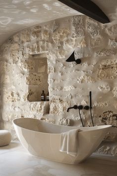 a large white bath tub sitting next to a stone wall