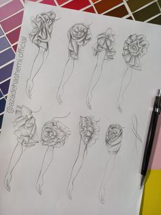 a drawing of different flowers on paper next to a pen