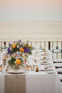 a table set up with plates and flowers on it