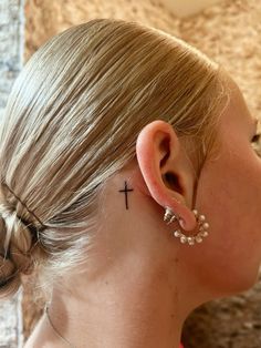 a woman with a cross tattoo behind her ear