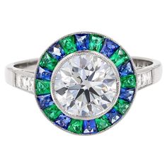 A Sophia D multi-gem art deco style ring featuring a round diamond surrounded with french cut emeralds and blue sapphires and emerald cut diamond set in platinum. Total center diamond weight: 1.84 carats Total emerald weight: 0.40 carats Total sapphire weight: 0.55 carats Total diamond weight: 0.23 carats Ring size is 6.5 and available for resizing Multi Gem Ring, Most Popular Engagement Rings, Gem Art, Popular Engagement Rings, Round Diamond Setting, Trending Engagement Rings, Art Deco Diamond Rings, Ring Trends, Gems Art