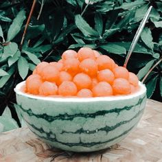 a watermelon bowl filled with lots of balls of ice on top of a wooden table