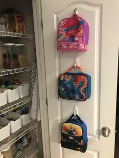 three children's backpacks are hanging on the door