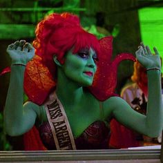 a woman with red hair and green makeup is dressed in costume for the miss america pageant