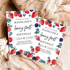 two birthday cards with strawberries and blueberries on them are sitting on a bed