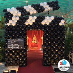 the entrance to an event decorated with balloons and black and white decorations on red carpet