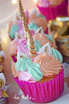 cupcakes decorated with pink, blue and green frosting are on a table