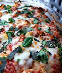 a pizza covered in cheese and spinach leaves