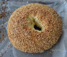 a sesame seed bagel sitting on top of a piece of wax paper