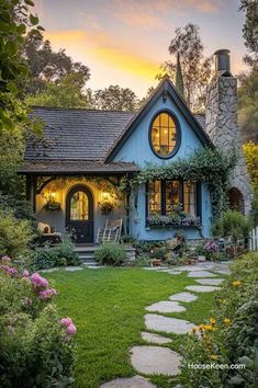 a small blue house with a stone pathway leading to the front door and windows that are lit up