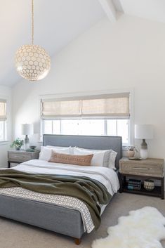 a bedroom with a bed, nightstands and two windows in the ceiling above it