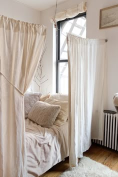 a white bed sitting under a window next to a radiator