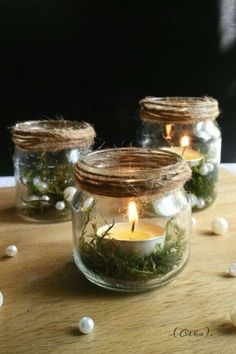 three mason jars filled with moss and lit candles