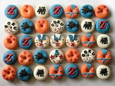 there are many decorated doughnuts on the white table top, one is blue and orange