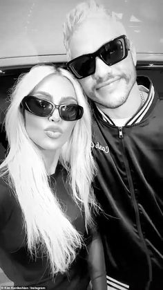 a man and woman posing for a photo in front of a car