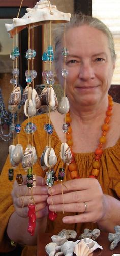 a woman sitting at a table with shells and beads