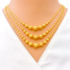 This magnificent 22k gold three Lara necklace set, weighing 35.4 grams, features a radiant yellow gold finish and a regal, gleaming design. The first row of the necklace measures 17 inches in length, while the last row measures 19 inches, with adjustable 0.6-inch links for a perfect fit. The set includes matching earrings, each 1.5 inches long with screw back posts and detachable hanging elements. Secured with a hook lock, this set is ideal for those who appreciate opulent and sophisticated jewe Elegant Yellow Gold Chain Necklace For Festivals, 22k Gold Round Beads Yellow Necklace, 22k Yellow Gold Round Beads Necklace, Yellow 22k Gold Necklaces With Round Beads, Elegant Gold Temple Necklace With Round Beads, Yellow 22k Gold Necklace With Round Beads, Yellow 22k Gold Round Necklace, Yellow Gold Necklace With Round Beads For Festivals, Bridal Jewelry Necklace