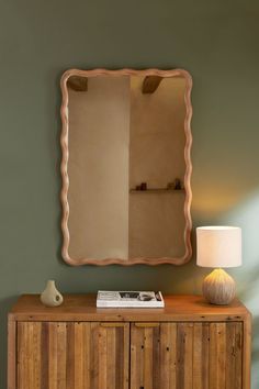 a wooden cabinet with a mirror on top of it and a lamp next to it