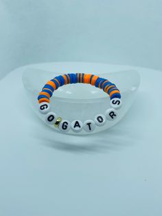 an orange, blue and white beaded bracelet with words on the end of it