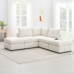 a white sectional sofa in a living room with windows and rugs on the floor