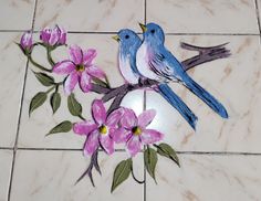 two blue birds sitting on top of a white tile floor next to pink and purple flowers