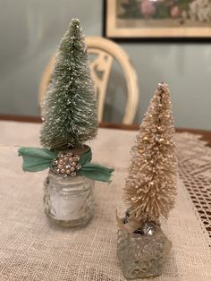 two small christmas trees sitting on top of a table