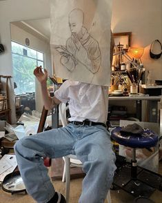 a man sitting in a chair holding up a drawing