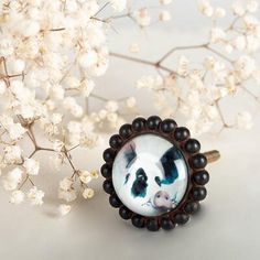 a panda bear ring sitting on top of a table next to white flowers and branches