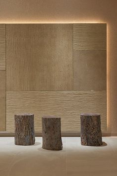 three wood stumps sitting in front of a wall