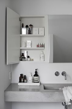 a white bathroom sink sitting under a mirror next to a shelf filled with personal care items