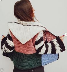 a woman wearing a multicolored sweater and holding a crocheted purse in her hands