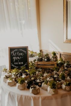 a table topped with potted plants next to a sign that says let love grow