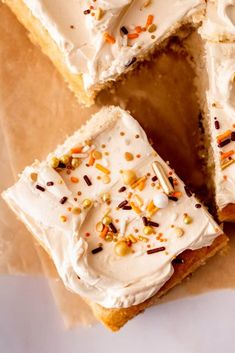 several pieces of cake with white frosting and sprinkles sitting on top of parchment paper