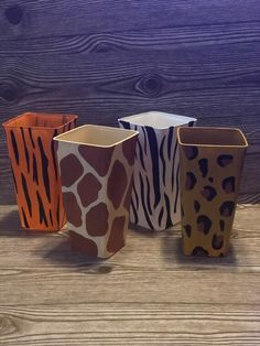 four animal print vases sitting on top of a wooden table