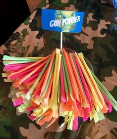 a bunch of colorful paper straws sitting on top of a camouflage tablecloth covered table