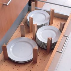 four plates are sitting on a rack in a kitchen with wooden cabinets and flooring