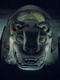 the head of an ancient statue is lit up in the dark room with only one eye visible