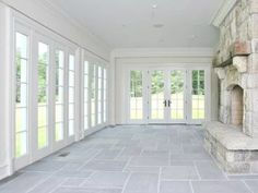 an empty room with large windows and stone bench in front of the door that leads to another room