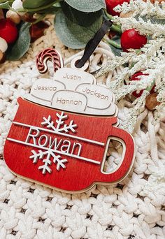 a christmas ornament sitting on top of a white blanket next to holly branches