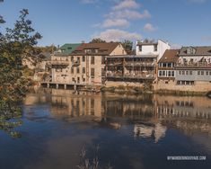 a river with buildings on both sides and trees in the foreground next to it