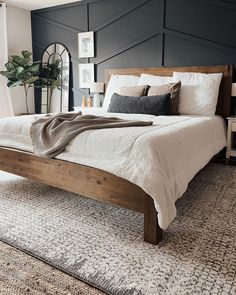 a bed with white sheets and pillows in a bedroom next to a rug on the floor