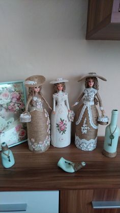 three dolls sitting on top of a wooden table next to vases and other items