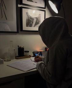 a person sitting at a desk in front of a laptop computer with a light on