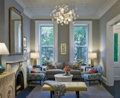 a living room filled with furniture and a chandelier hanging from the ceiling over a fire place