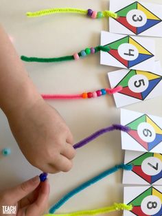 a child's hand is pointing at the numbers on their colorful beaded bracelets