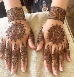 two hands with henna tattoos on them, one is showing it's intricate designs