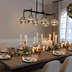 a dining room table is set with candles and plates