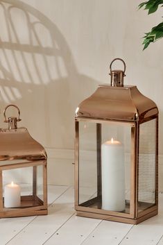 two metal lanterns sitting on top of a white tile floor