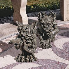 two gargoyle statues sitting next to each other on top of a tiled floor